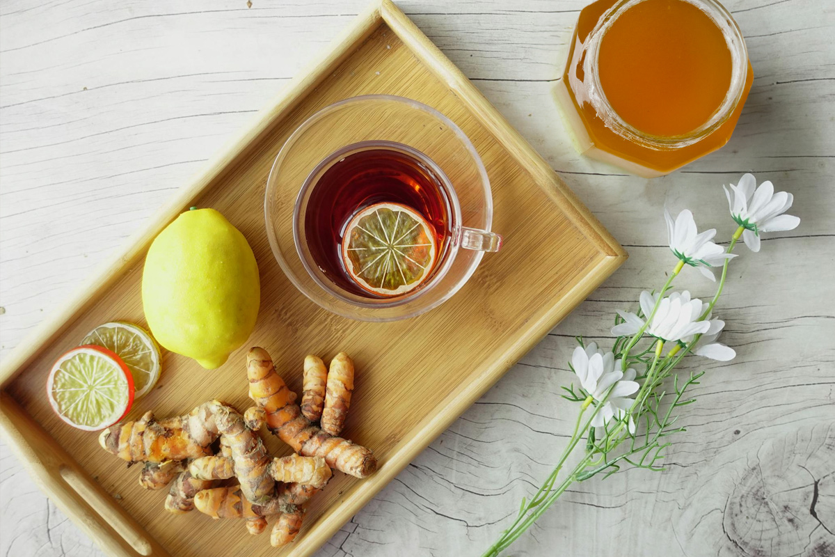 A pot of ginger tea, teacup on the side, slices of Ginger on the side